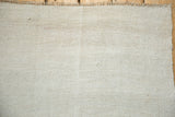 The plain-weave texture and secured corner of a vintage hand-woven hemp kilim.