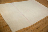 Angled perspective of a vintage Turkish hemp kilim with a natural, plain-weave body and soft pink striping.