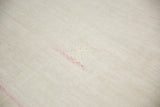 A pink stitched design element on the neutral-toned plain-weave of a vintage hemp kilim.
