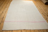 Angled perspective view down the length of the vintage ivory and pink striped kilim.
