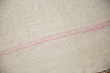 Close-up showing the plain-weave texture and soft pink stripes of a vintage hemp kilim.