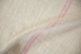 Detail of the soft pink horizontal stripes on the textured plain-weave of a vintage hemp kilim.