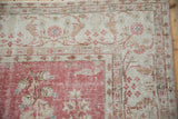 Distressed Oushak carpet with a pale raspberry red field and ivory arabesque border.
