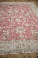 Distressed vintage Oushak carpet showing faded floral blossoms and delicate vines.