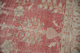 Faded raspberry red distressed Oushak rug pile with delicate floral vines and arabesque border.