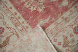 Distressed vintage Oushak carpet, raspberry and ivory floral pile, machine-bound edge, and woven reverse.