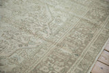 Distressed vintage Tabriz carpet showing faded beige field and subtle botanical vinery.
