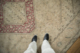 Distressed vintage Turkish Tabriz rug showing beige Herati field and raspberry red geometric border.