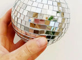 A medium disco ball held in hand, showing the mosaic of small mirrored squares.