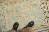 Worn texture of a distressed Oushak rug underfoot, in cream, mint green, and pale coffee brown hues.