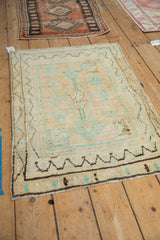 Angled perspective of a vintage distressed Oushak rug with a mint green tree of life design.
