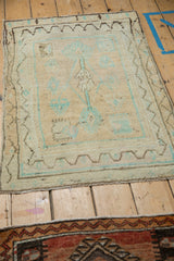 Angled perspective of a small distressed Oushak rug with a tree of life design.