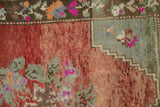 Distressed Oushak rug pile with abrashed brick red field and seafoam green floral details.