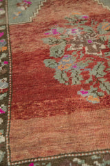 Distressed Oushak rug showing textured pile, abrashed brick red field, and seafoam floral motif.