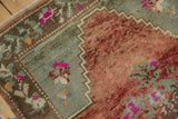 Distressed Oushak rug detail: abrashed brick red field, seafoam green border, bright fuchsia, and intact selvage.