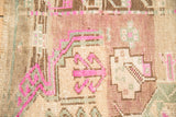 Textured close-up of distressed Kars rug's geometric shapes in magenta, beige, and seafoam green.