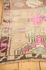 Distressed vintage Kars rug showing camel, magenta, seafoam green geometric patterns and low pile.