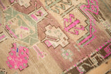 Distressed Kars rug's fuchsia gul and seafoam green geometric pattern detail.