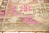 Distressed Kars rug pile featuring geometric magenta and seafoam green motifs on a camel ground.