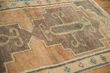 Vintage Kars rug's stepped medallion, showing scrolled tendril motifs in dusty teal on charcoal.