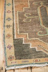 Corner detail of vintage Kars runner, pale coffee brown border, pink, dusty teal geometric motifs, fringe.