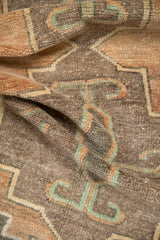 Textured hand-knotted pile in brown, charcoal, and dusty teal stepped patterns.