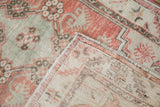 Textured pale red and seafoam green pile of Oushak rug runner, revealing striped reverse foundation.