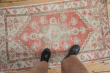 Distressed vintage Oushak rug close-up with blush and ivory geometric pattern and even wear.