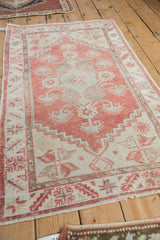 Distressed blush Oushak rug border showing serrated leaf motif and worn pile.