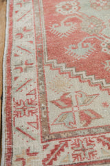 Blush serrated leaf border and inner serpent motif on a distressed Oushak rug.