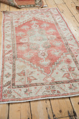 Distressed Oushak rug's finned blossoms, serpent, and serrated leaf motifs in ivory and blush.