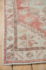 Worn side selvage of a vintage distressed Oushak rug, with blush and beige serrated leaf border.