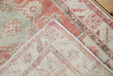 Distressed hand-knotted Oushak rug corner showing worn blush pile and exposed foundation.