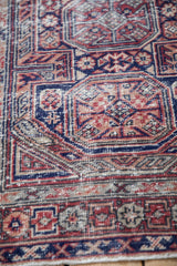 A detailed angle on the cobalt blue and cherry red patterns showing the rug's even wear.