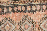 Close-up of a distressed Oushak rug showing worn texture, a zig-zag border, and geometric motifs.