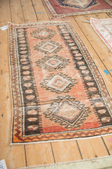Angled view of a vintage Oushak runner showing its repeating hook and latch diamond medallions.