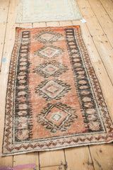 A vintage distressed Oushak runner with a terracotta field and bold geometric diamond medallions.