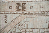 Close-up of distressed Oushak rug showing chocolate brown geometric motifs on antique ivory with worn pile.