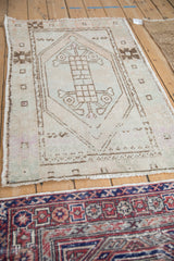Distressed corner of vintage Oushak rug, with geometric patterns and time-softened tones.