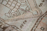Close-up of distressed vintage Oushak rug's hand-knotted pile, geometric serpent elements, and soft colors.