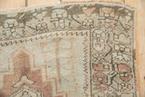 Distressed Anatolian rug corner with serrated border, dusty blush, ivory, and coffee brown geometric motifs.