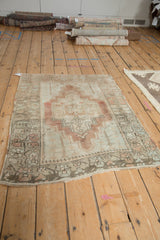 Distressed vintage Anatolian rug corner showing tree of life spandrel, serrated border, dusty blush, ivory.