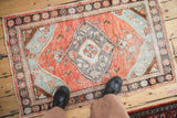 Distressed vintage Oushak rug, worn pile in brick red-orange and seafoam green.