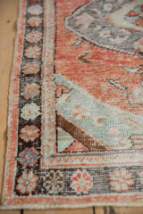 Distressed Turkish Oushak rug corner, brick red, seafoam green, charcoal floral patterns, worn pile.