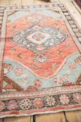 Charming, distressed Oushak rug featuring brick red orange and seafoam green floral medallion.