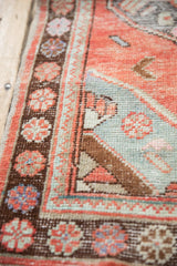 Distressed Oushak rug: worn brick red orange field with floral and seafoam green border.