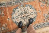 Distressed vintage Oushak rug, rust and ivory field, blue fern patterns, worn texture.