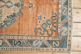 Distressed Oushak rug corner, rust field, denim blue serpent border, pale turquoise cloudbands.
