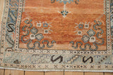 Distressed Oushak rug corner, rust field, pale turquoise motifs, denim blue geometric border.
