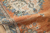 Folded distressed Oushak rug with rust, denim blue, ivory geometric border and worn pile texture.